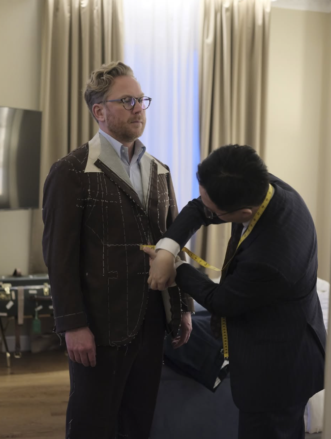 台北西裝訂製量身服務，訂製師測量顧客腰圍並調整半成品西裝版型